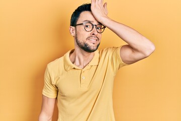 Young hispanic man wearing casual clothes and glasses surprised with hand on head for mistake, remember error. forgot, bad memory concept.