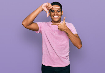 Young handsome hispanic man wearing casual pink t shirt smiling making frame with hands and fingers with happy face. creativity and photography concept.