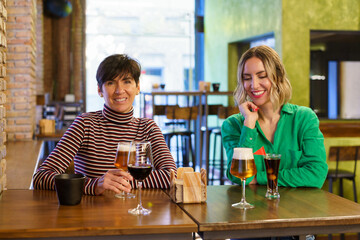 Cheerful girlfriends sitting at table in bar