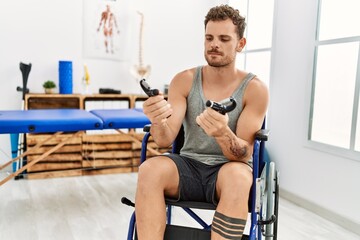 Young hispanic man doing rehab using hand grip sitting on wheelchair at clinic