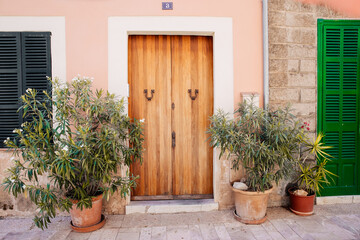 door with flowers. Large wooden front door with oleander plants in pots. House by the lake in Italy, Greece or Spain. Entrance door nicely decorated with plants and flowers.	