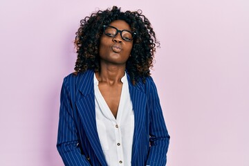 Young african american woman wearing business clothes and glasses looking at the camera blowing a kiss on air being lovely and sexy. love expression.