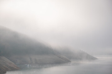Soft, abstract, minimalist, misty view of a raft on an evaporating lake on a foggy morning with a lot of copy space