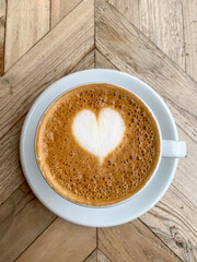 A mug of flat white or latte art coffee on a wooden background. Coffee art. Heart flower shape latte art