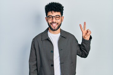 Young arab man with beard wearing glasses smiling with happy face winking at the camera doing...