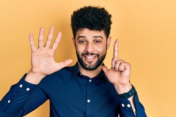 Young arab man with beard wearing casual shirt showing and pointing up with fingers number seven while smiling confident and happy.