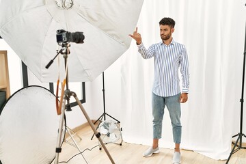 Arab young man posing as model at photography studio showing middle finger, impolite and rude fuck...