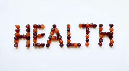 A group of red, orange and purple multivitamin gummies laid out in the form of the word health