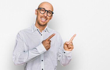 Bald man with beard wearing business shirt and glasses smiling and looking at the camera pointing with two hands and fingers to the side.