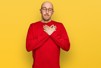 Bald man with beard wearing casual clothes and glasses smiling with hands on chest with closed eyes and grateful gesture on face. health concept.