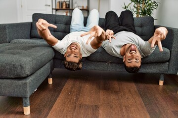 Two hispanic men couple smiling confident lying on sofa at home