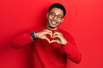 Young african american man wearing casual clothes and glasses smiling in love doing heart symbol shape with hands. romantic concept.