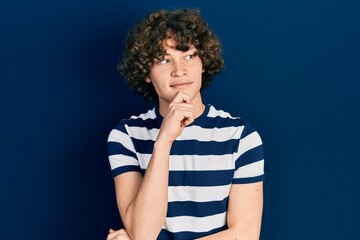Fototapeta na wymiar Handsome young man wearing casual striped t shirt with hand on chin thinking about question, pensive expression. smiling with thoughtful face. doubt concept.