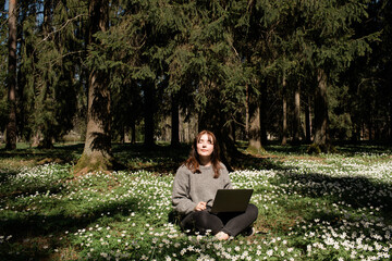 Digital nomad. Woman using laptop and phone next to the spring nature background. Social media...