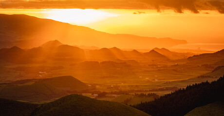 Naklejka premium Sunrise over landscape with mountains, orange light, sun rising.