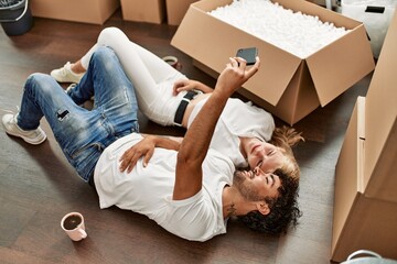 Young beautiful couple smiling happy making selfie by the smartphone at new home.