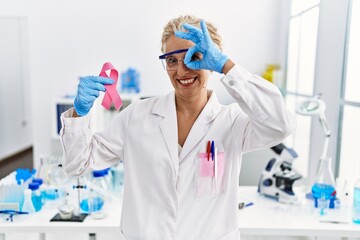 Middle age blonde woman working at laboratory looking for breast cancer cure smiling happy doing ok...