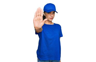 Young hispanic girl wearing delivery courier uniform doing stop sing with palm of the hand. warning expression with negative and serious gesture on the face.
