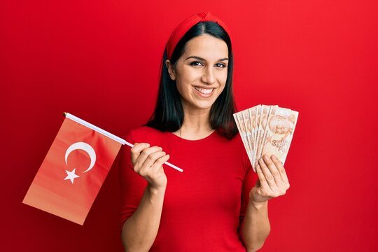 Young hispanic woman holding turkey flag and liras banknotes smiling with a happy and cool smile on face. showing teeth.