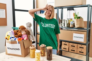 Young caucasian woman wearing volunteer t shirt at donations stand doing ok gesture with hand...