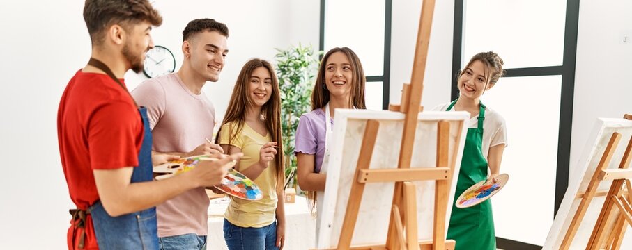 Group of people smiling happy drawing on canvas standing at art studio.