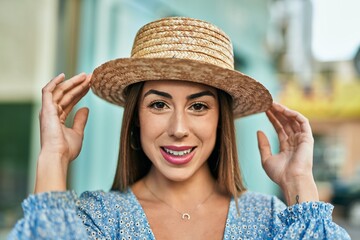 Young hispanic woman wearing summer hat smiling happy  at the city.