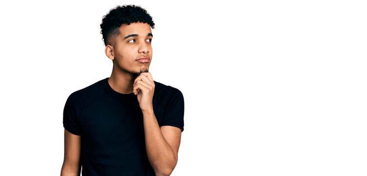 Young african american man wearing casual black t shirt thinking concentrated about doubt with finger on chin and looking up wondering
