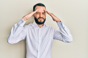 Young man with beard wearing business white shirt with hand on head, headache because stress. suffering migraine.