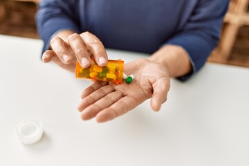 Woman taking pills sitting on the table at home.
