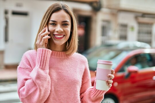 Young caucasian girl talking on the smartphone and drinking coffee at the city.