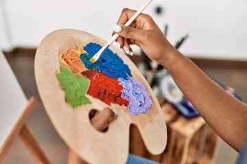 Young african american woman mixing color on palette at art studio