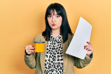 Young hispanic woman wearing business style drinking cup of coffee puffing cheeks with funny face....