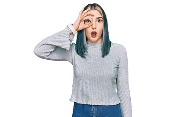 Young modern girl wearing casual sweater doing ok gesture shocked with surprised face, eye looking through fingers. unbelieving expression.