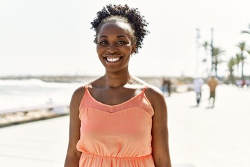 Young african american woman smiling happy on a summer day by the beach