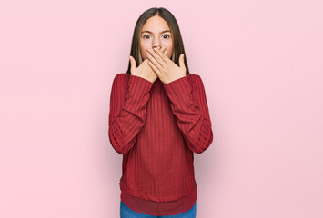 Beautiful brunette little girl wearing casual sweater shocked covering mouth with hands for mistake. secret concept.