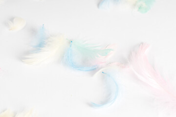 small colored feathers, on a white background, there is a place for text. Top view Easter concept