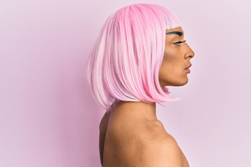 Hispanic transgender man wearing make up and pink wig looking to side, relax profile pose with natural face with confident smile.