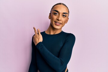 Obraz premium Hispanic man wearing make up and long hair wearing casual clothes smiling cheerful pointing with hand and finger up to the side