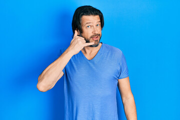 Middle age caucasian man wearing casual clothes smiling doing phone gesture with hand and fingers like talking on the telephone. communicating concepts.