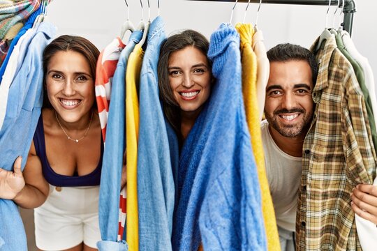 Young hispanic people smiling happy appearing through clothes at fashion store.