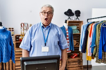 Senior man with grey hair working as manager at retail boutique afraid and shocked with surprise expression, fear and excited face.