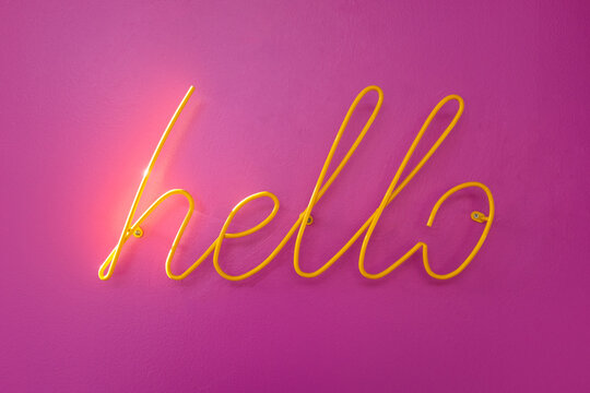 Wall-mounted metal "hello" sign on a pink wall