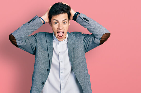 Young hispanic man wearing business clothes crazy and scared with hands on head, afraid and surprised of shock with open mouth