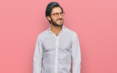 Young hispanic man wearing business shirt and glasses looking away to side with smile on face, natural expression. laughing confident.