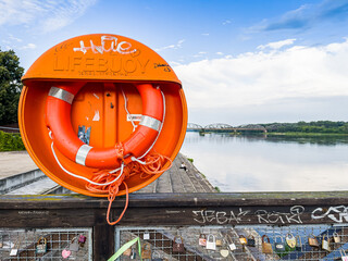 Torun, Poland - August 11, 2021. Orange lifebuoy in riverbank by river Wisla