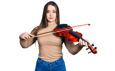 Young hispanic girl playing violin relaxed with serious expression on face. simple and natural looking at the camera.