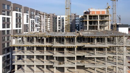 Aerial view of concrete frame of tall apartment building under construction in a city.