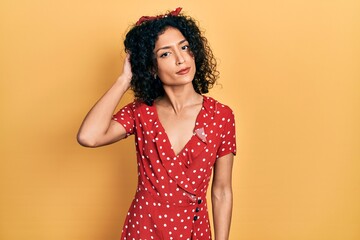 Young latin girl wearing summer dress confuse and wondering about question. uncertain with doubt,...