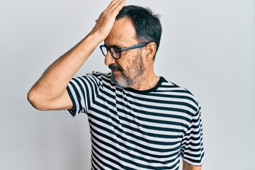 Middle age hispanic man wearing casual clothes and glasses surprised with hand on head for mistake,...