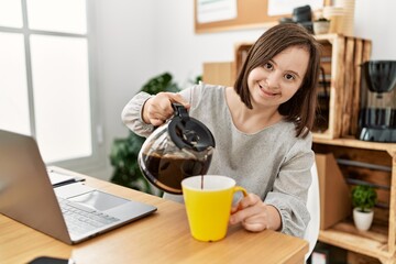 Brunette woman with down syndrome drinking a cup of coffee at business office